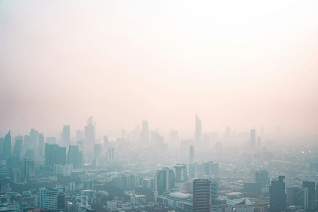 city skyline under white smog during daytime, bad air quality is a good reason to close the windows and turn on the ac, ac has filters with high MERV value to clean the air inside the house and improve air quality Photo by Nick van den Berg