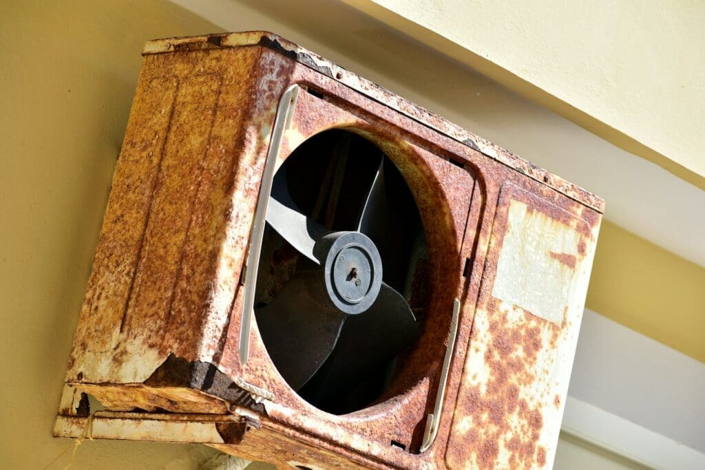 Photo by Ries Bosch a rusted metal fan mounted to the side of a building air conditioner, global warming, summer ac repair hollywood fix ac in hollywood ac install air conditioner install Hollywood air conditioner repair fan ac repair